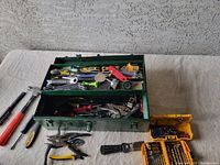 Full view of green metal toolbox with assorted hand tools inside including pliers, screwdrivers, and drill bit set
