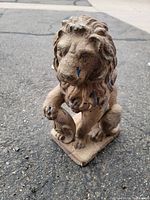 Front view of the small lion statue showing detailed mane and paint chipping with patches of blue paint.
