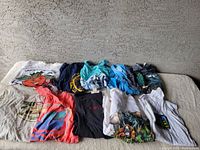 Photo showing a collection of ten vintage graphic t-shirts laid out together featuring the 1985 Orange Bowl and other travel-related prints in various colors