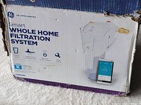 Box showing GE Appliances Smart Whole Home Filtration System, model GXWH40K and key features of the product such as filter life label, water flow and filter detection, customizable water usage reports.