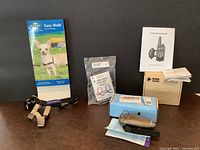 Overall lot showing Easy Walk harness, Sensation harness unopened, no shock bark control collar with remote, and handheld bark control device with manuals