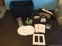 Various electrical items shown including wall plates, cords, connectors, and tools arranged on a table.