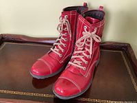 Pair of red leather boots angled to show the front and tops with laces tied.