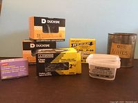 Photo of assorted boxes and container of nails and fasteners showing brands Duchesne, SIVACO, Arrow, and a labeled plastic container.