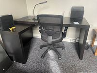 Photo of single Ikea Malm desk showing black-brown finish, pull-out panel, and surroundings including office chair and desk lamp.