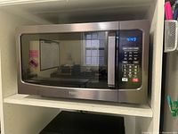 Front view of Toshiba convection microwave oven placed in a shelf, showing black stainless steel finish, control panel with digital display and buttons.