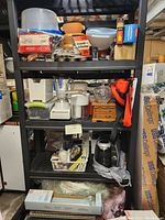 Photo of black metal shelving unit with various kitchen items and other miscellaneous items on the shelves, but the items are excluded from the lot per seller instructions.