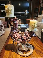 Photo showing the decorative candle holder with two cream-colored pillar candles that feature gold snowflake embellishments.