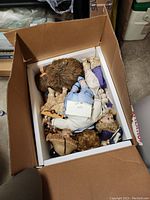 Photo of a box filled with multiple assorted dolls with varying hair colors and clothing styles