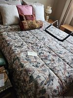 Photo of double bed with floral pattern mattress, assorted pillows, and metal frame showing mattress optionally included.