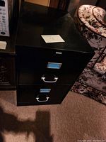 Black 2-drawer metal file cabinet showing top and front with labels and handles