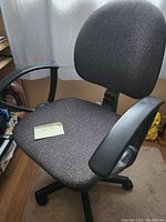 Gray fabric office chair with black adjustable armrests and cushioned seat and backrest