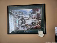 Framed landscape painting showing a house by a waterfall and river, green and black frame