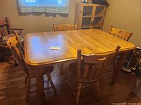 Angle view of the solid wood dining table and chairs showing table shape and leg design