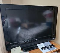 Photo showing Sony Bravia TV on table with remote and manual in front.
