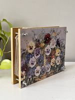 Side angle showing the floral artwork on the acrylic top of the vintage flower press, metal corner screws visible to tighten the press.