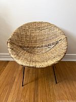 Front view of round wicker papasan chair with metal legs on a wood floor interior