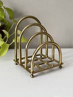 Front side view of the vintage brass letter holder showing four rounded compartments and base with grid pattern.