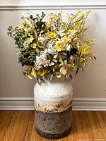 Full view of large vintage milk jug filled with faux flowers, showing size and color contrast.