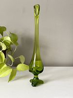 Full view of the green glass swung vase standing vertically showing its elongated shape and wide base.