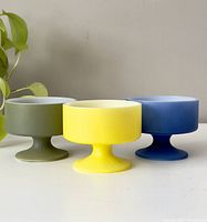 Front view of the three vintage stacking cups in green, yellow, and blue colors, shown side by side.