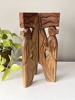 Front view of the wooden tri fold plant stand showing carved bird figures on hinged sections.
