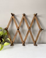 Front view of wooden accordion peg rack showing diamond pattern with 10 pegs