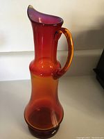 Full view of the amber glass vase showing red to orange gradient and handle