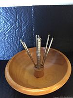 Wooden nut bowl with metal center holding nutcracker and four nut picks