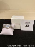 Fossil BQ1600 women's wristwatch displayed on a white pillow in front of white Fossil box and auction lot number card.