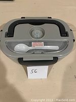 Closed gray heated lunch box showing black handle and spoon in lid compartment.
