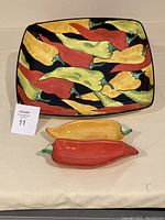 Two-piece chip and dip set showing the colorful chili pepper pattern on the platter and the two chili-shaped dipping bowls.