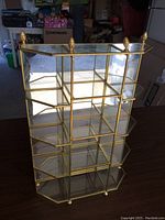 Front and side view of the glass and brass curio cabinet showing open concept and mirrored back panel