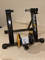 Side angle showing Minoura Mag Turbo E750 bike trainer stand details with visible pedals and resistance unit.