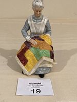 Front view showing elderly woman sewing colorful patchwork quilt