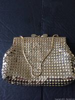 Front view of vintage gold metallic mesh evening bag with snake chain handle against a black background.