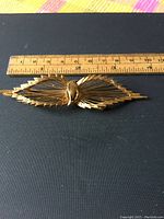 Top view of the vintage Marcel Boucher brooch next to a ruler showing approximately 4 inches width