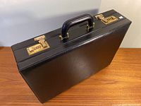 Photo showing entire closed briefcase with handle and two combination locks on the front.