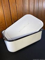 White enamel rectangular metal pan with black trim and matching lid, shown with lid resting inside the pan.