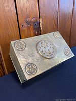 Top angled view showing the brass box lid engraved with bird and dragon motifs, four circular medallions with Chinese characters, and central carved white jade inset.