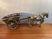 Full profile view of the heavy brass Shire horse pulling a cart sculpture placed on a wooden surface.