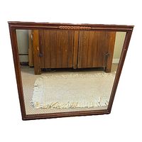 Straight-on view of square ornate framed mirror showing the carved top accent and polished wooden frame.