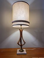 Full view of the Mid Century Modern teak table lamp lit, showing burlap shade and lamp's height and structure.