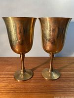 Front view of two brass chalices side by side showing their size, shape, and reflective surface.