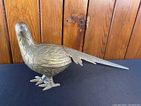 Front-side view of the brass pheasant bird figurine showing detailed feather engraving and shape.