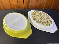 Top view of the oval Pyrex dish showing the green exterior and white divided interior along with the decorative olive plant pattern lid.