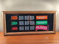 Front view of framed vintage slot machine backglass showing payout sign and BAR symbols.