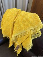 Vintage yellow and orange Mexican blanket with geometric pattern shown draped and folded. The blanket has fringed edges and measures approximately 76 x 56 inches.