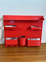 Front view of red plastic wall organizer showing all compartments and hooks