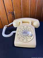 Yellow Bell Canada rotary dial telephone seen from front and side angle showing the rotary dial and handset resting on top.